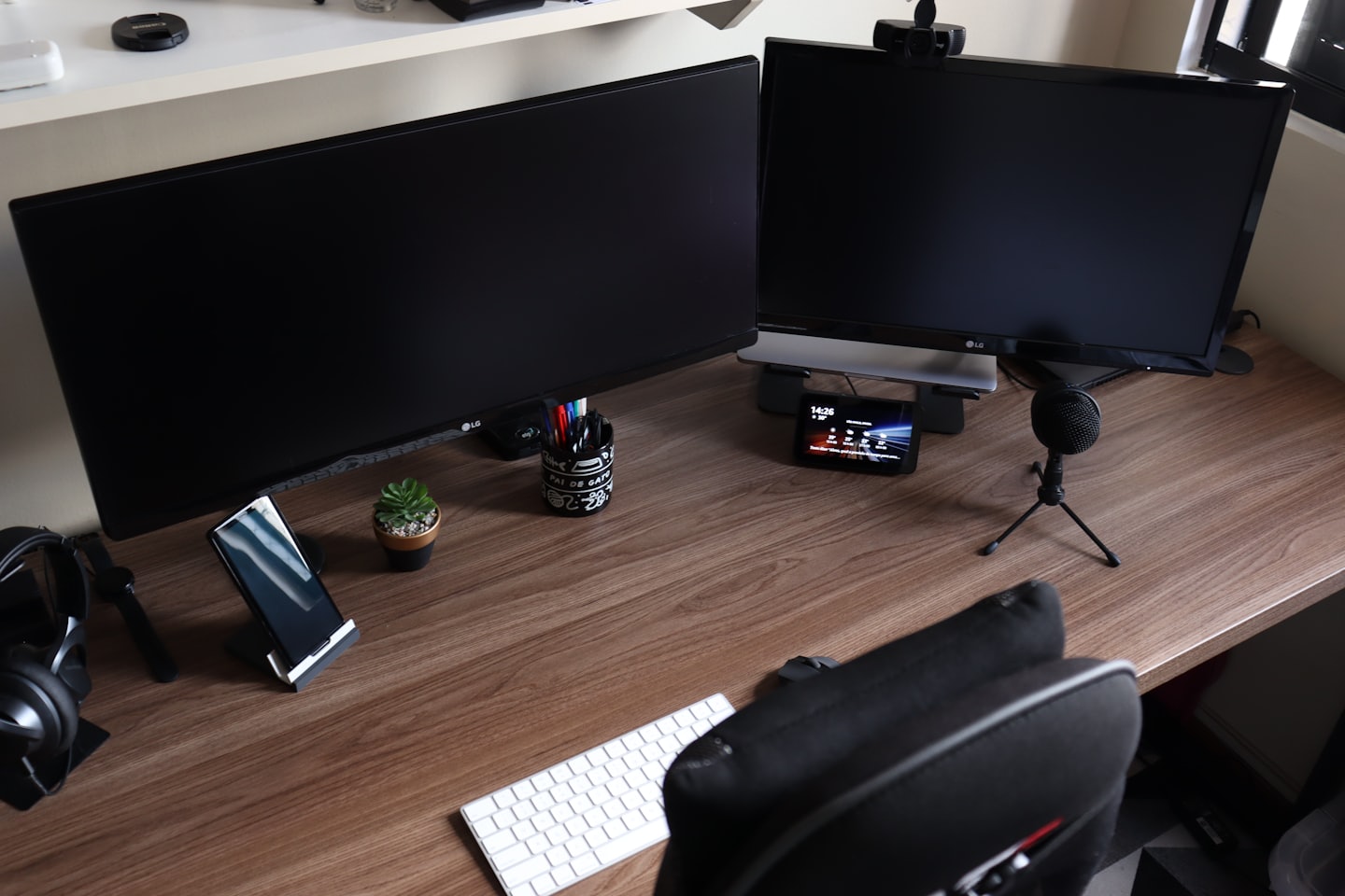 Escritorio ordenado con computadoras, teclado, auriculares y una suculenta.